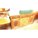 Sideboard in mixed woods with ornately carved front of double cabinet beside two lower drawers with