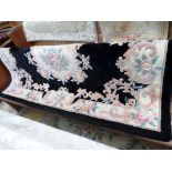 Black ground carpet in similar style with multi coloured floral rosette to central field with