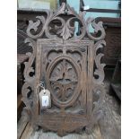 Ornately carved small shelved wall cabinet in the black forest style
