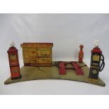 A Marx tinplate model of a service station with petrol pumps and globes.