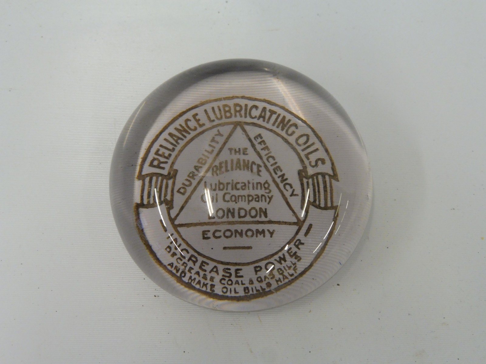 A Reliance Lubricating Oil Company of London glass paperweight.