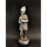 A vintage car accessory mascot in the form of a highland soldier holding a rifle, worn chrome plated