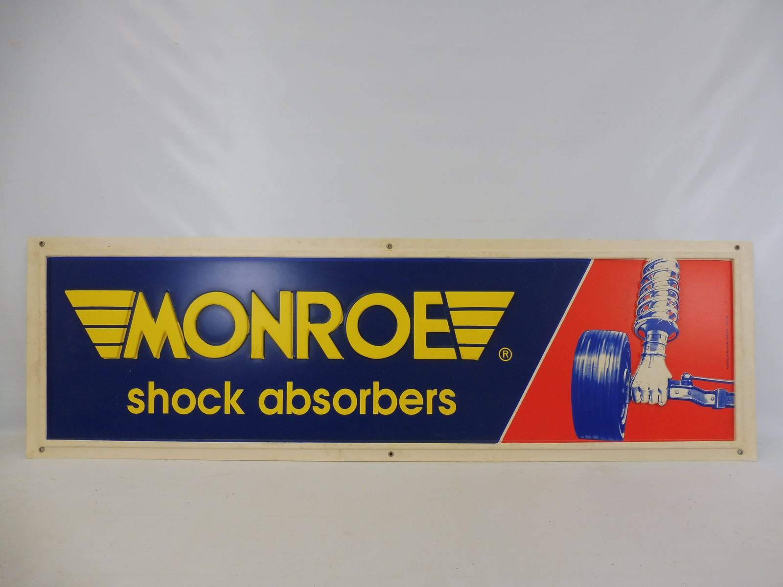 A Monroe shock absorbers embossed plastic sign, 51 x 15 1/2".