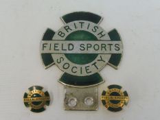 A British Field Sports Society enamel car badge and two matching lapel badges.
