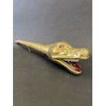 A brass horn in the form of a Boa Constrictor with red eyes.