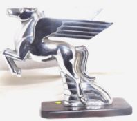 An accessory mascot in the form of a stylised pegasus, display base mounted.