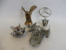 A MACK lorry mascot, a Mercedes-Benz badge and two further mascots.