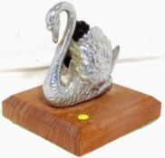 An accessory mascot in the form of a swan, on a display base.