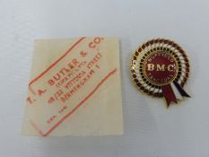 A BMC Nuffield Tractors enamel lapel badge in original paper packet.