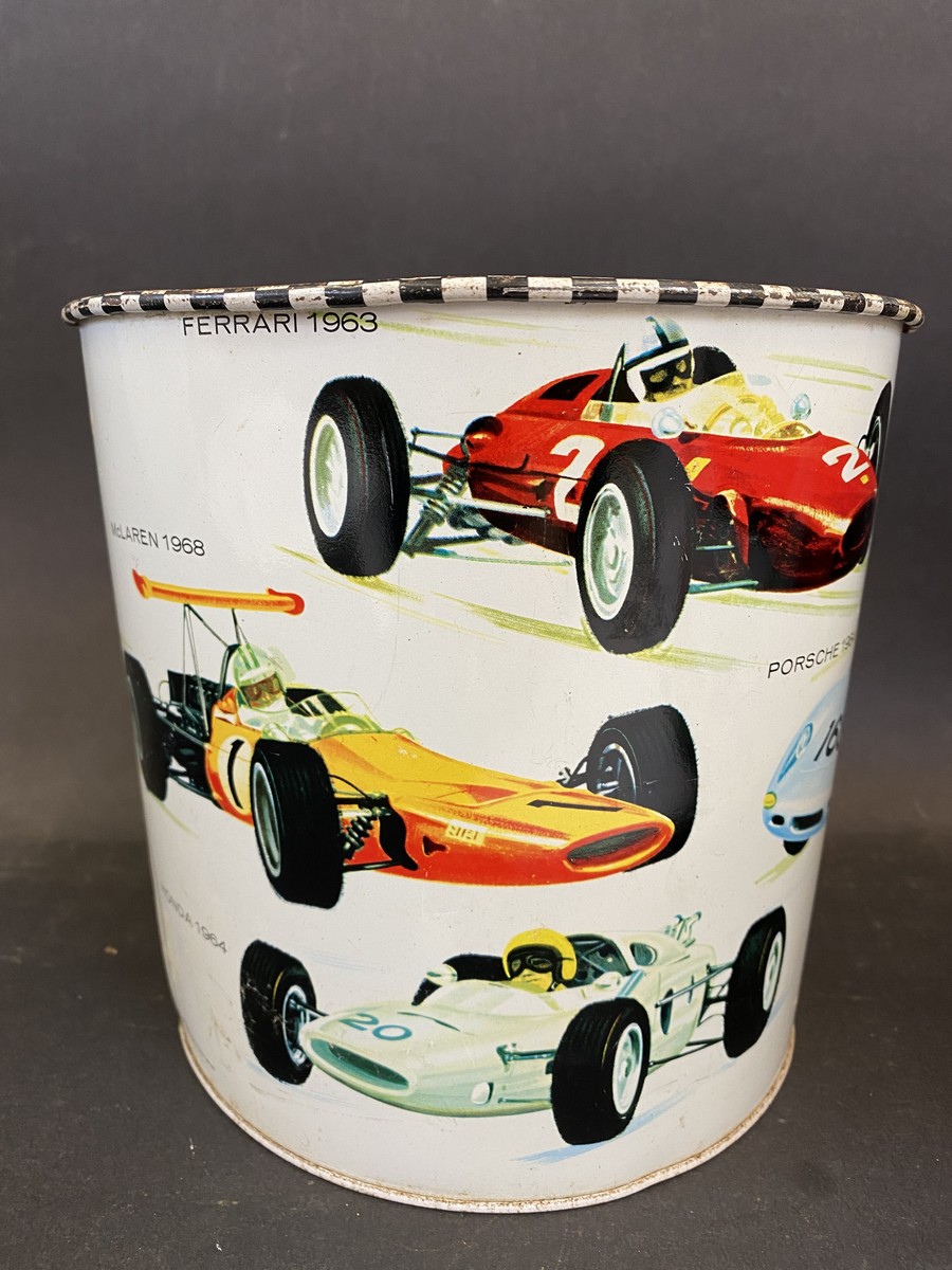 A waste paper bin decorated with Formula 1 race cars from the 1960s, 7" high.