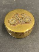 A small brass pill pot with a lady's bicycle image to the lid.