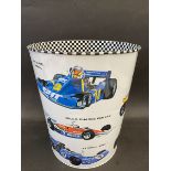 A waste paper bin decorated with Formula 1 race cars from the 1970s and 1980s, 10" high.