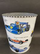 A waste paper bin decorated with Formula 1 race cars from the 1970s and 1980s, 10" high.