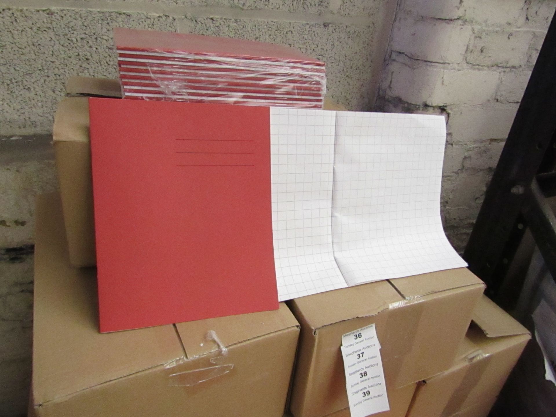 100x Red coloured exercise books, new and boxed.