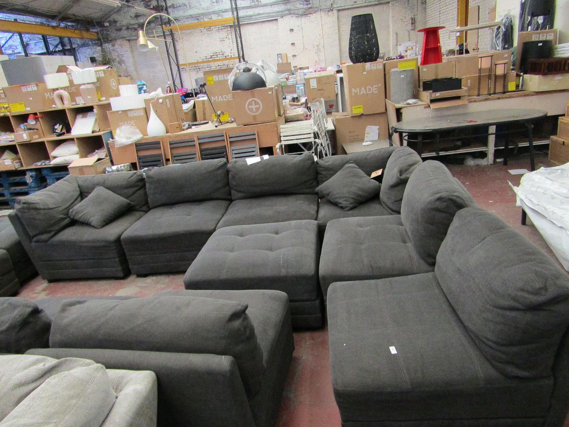 Dark grey M star sectional sofa, features 6 sectional pieces and a footstool, missing one foot.