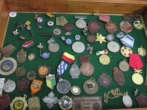 Wooden display case containing a variety of medals & badges. Estimate £20-30