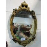 Oval wall mirror in gilt frame, decorated with putti, 69 x 44. Estimate £20-30
