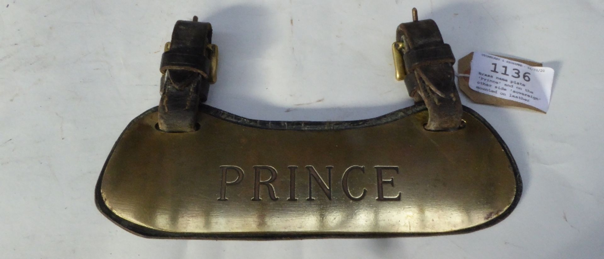 Brass name plate 'Prince' and on the other side 'sovereign' mounted on leather