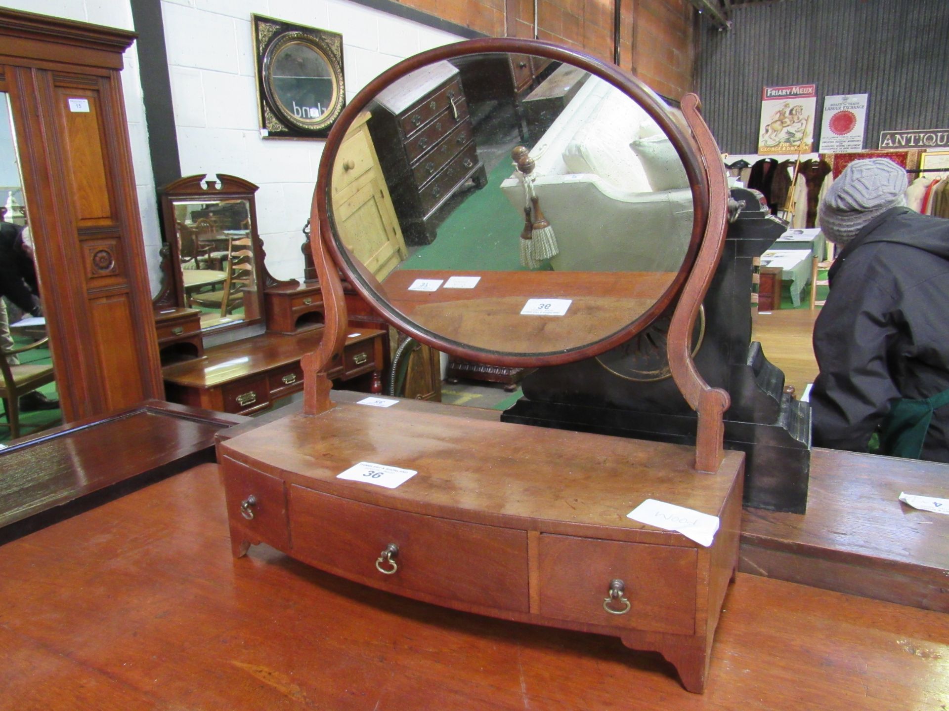 Walnut toilet mirror on shaped supports and three frieze drawers. Estimate £20-30.