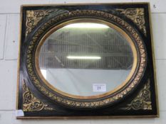 Ebonised oval mirror with gold foliage in a square frame with gold spandrels. Estimate £50-60.