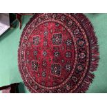 Round deep pile fireside rug in deep red with lozenge design. Diameter 137cms. Estimate £20-30.