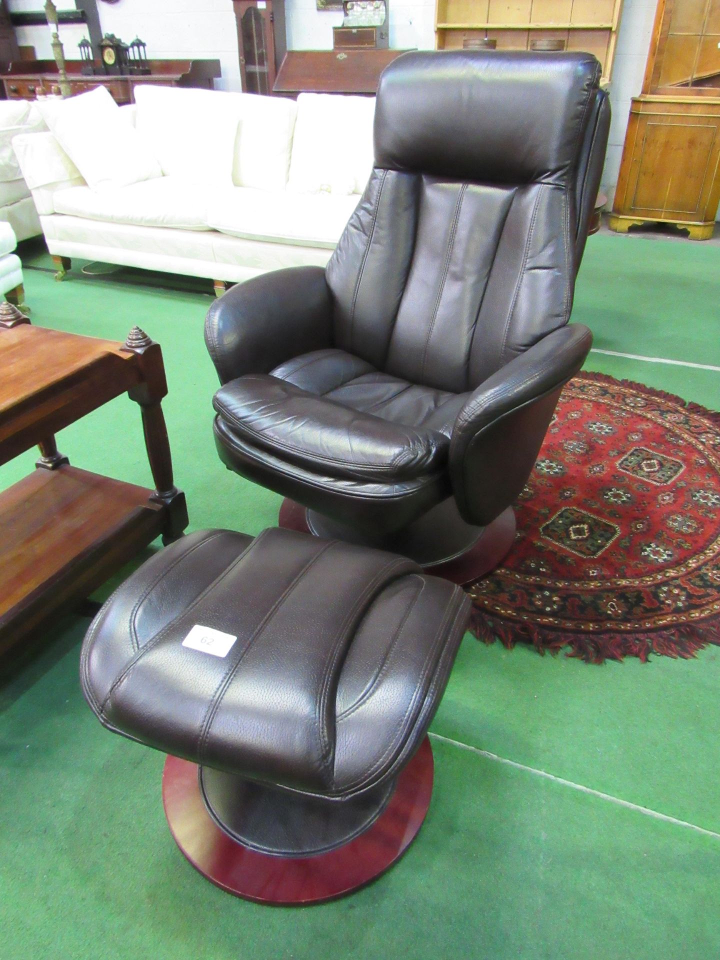 Dark brown leather-effect swivel chair and footstool. Estimate £30-50.
