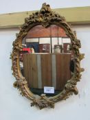 Oval ornate gilt framed wall mirror. Estimate £10-20.