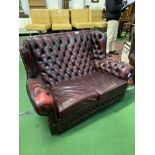Red leather button back 2 seat sofa and matching armchair. Estimate £50-100.