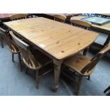 Pine extending kitchen table with six farmhouse chairs.