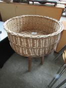 Wicker basket on stand, diameter 56cms, height 73cms.