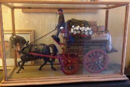 A detailed model of a Fruiterers & Greengrocers cart with driver and horse displayed in a glass