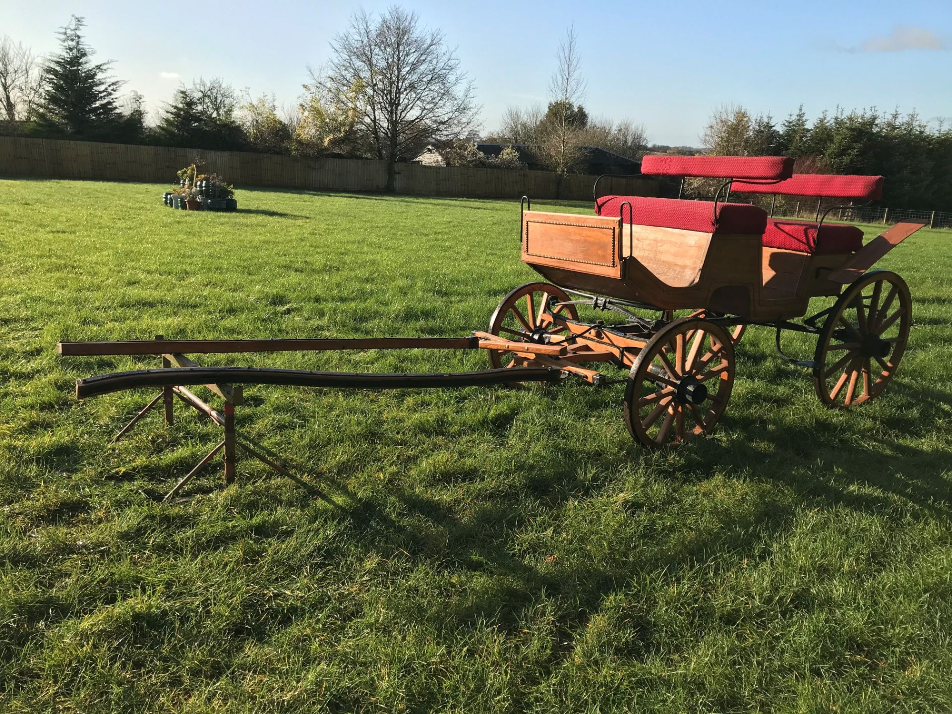 FOUR-WHEEL PLEASURE VEHICLE finished in natural varnished wood edged in carved detailing, and red