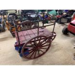 MILK PRAM with open railed sides and pram handle. Painted burgundy with cream lines to the wheels.