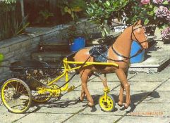 Early 20thC child's ride-on pedal horse in harness with driving reins, pulling a two-wheel pedal