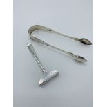 Georgian silver sugar tongs, 1.5ozt, together with a silver child's food ""pusher"", 0.5ozt.