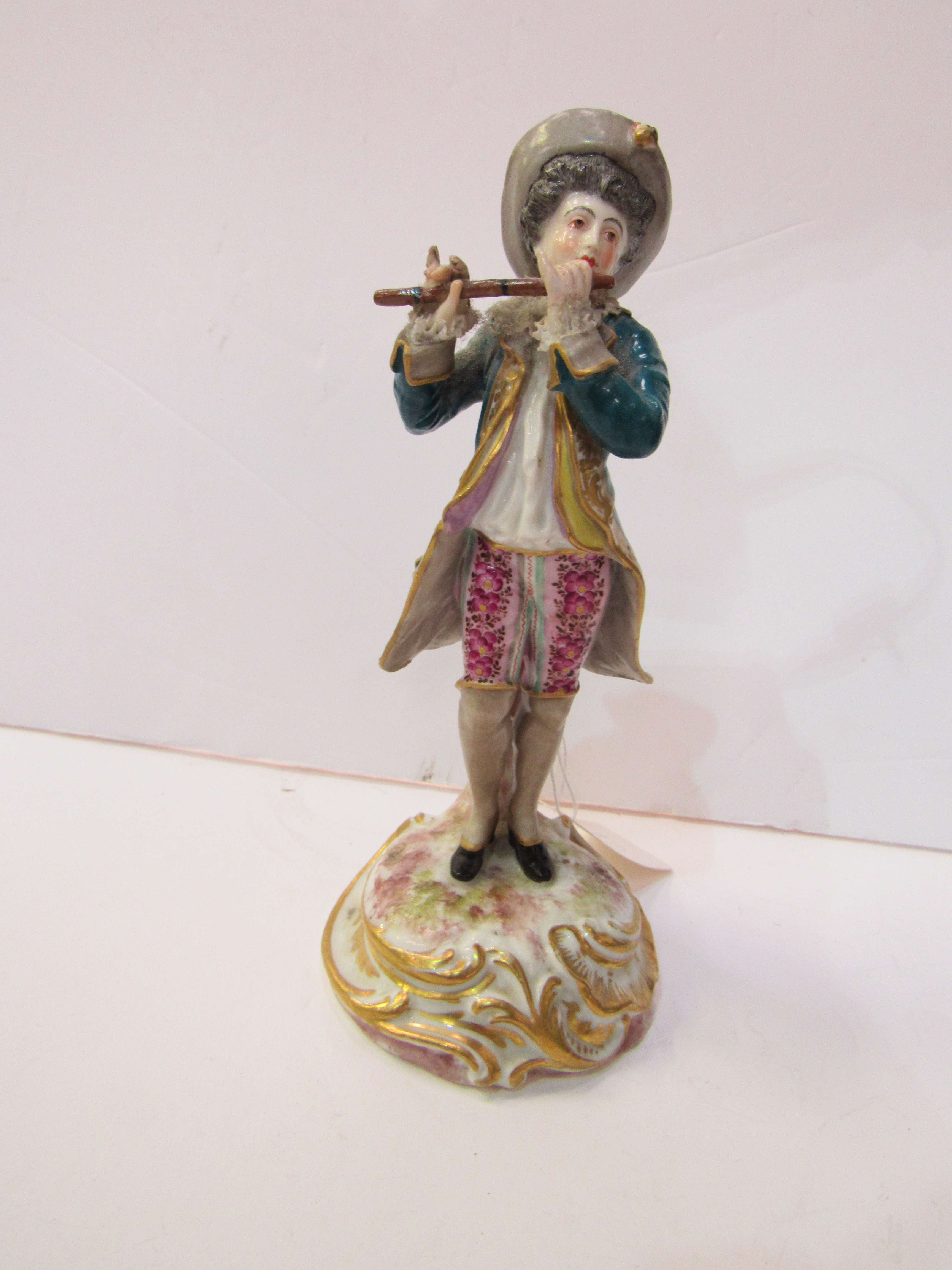 19th Century Meissen figure of a man playing a flute. Estimate £60-80.
