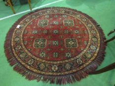 Round deep pile fireside rug in deep red with lozenge design. Diameter 137cms. Estimate £20-30.