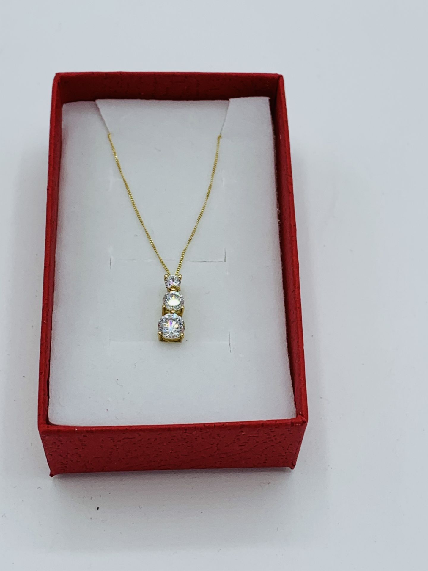 9ct gold pendant necklace set with three zircon stones. Estimate £30-40.