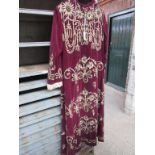 Burgundy velvet robe with gold embroidery and lace cuffs.