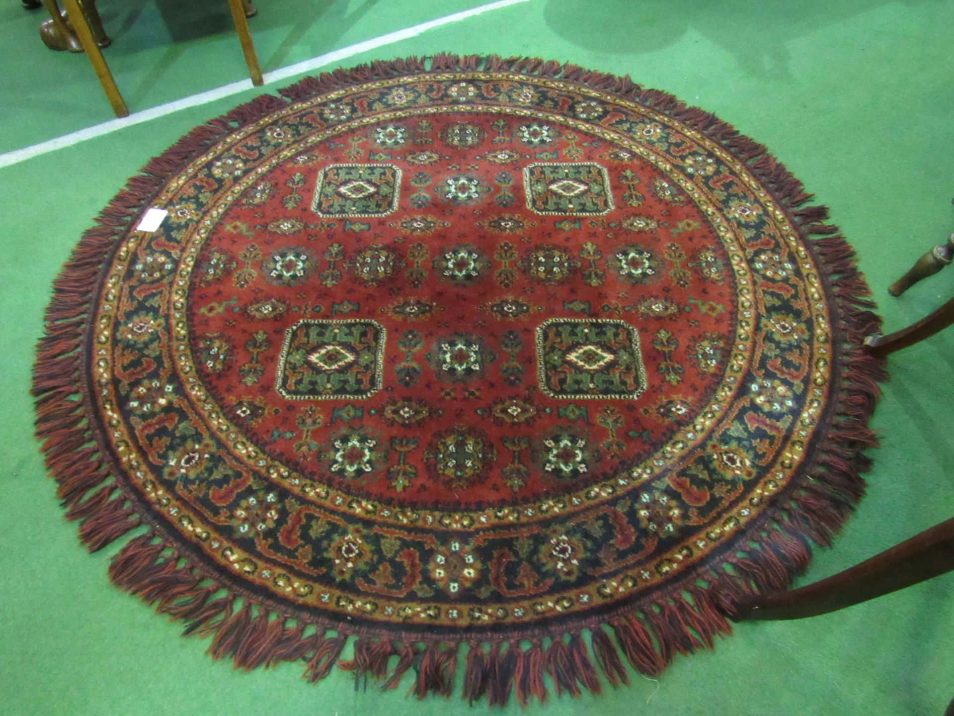 Round deep pile fireside rug in deep red with lozenge design.