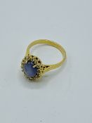 750 gold ring set with pale blue marbled stone surrounded with diamond chips