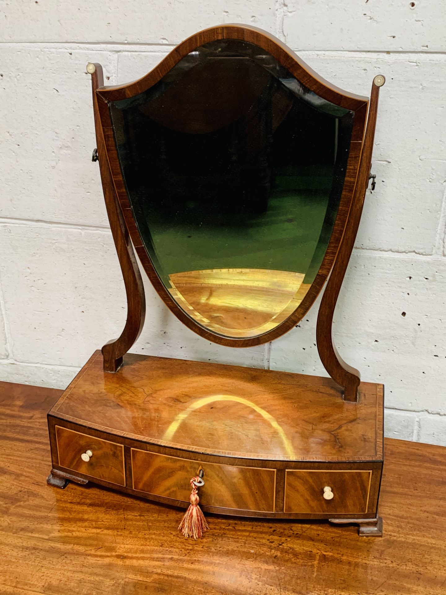 Mahogany shield shaped toilet mirror with 3 drawers to base.