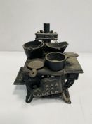 "Queen" miniature cast iron stove, complete with miniature saucepans.