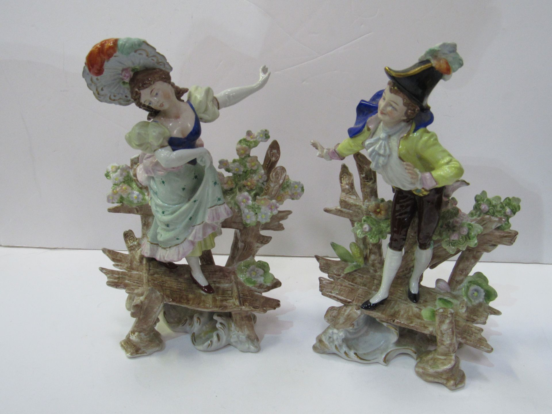 Pair of Scheibe-Alsbach figurines of a girl standing on a bench and boy standing on a bench.