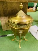 A large brass covered urn on a four legged stand.