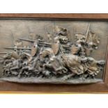 A framed relief panel depicting a mediaeval cavalry charge, 27 x 49cms. Estimate £20-40.