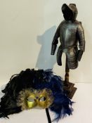 A Venetian mask together with a model of a civil war suit of armour on a stand.