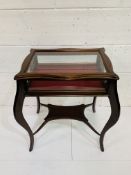Mahogany bow legged glass topped display cabinet, with under shelf.