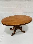 Mahogany oval tilt top table on carved pedestal to four feet.