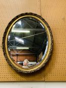 An oval gilt framed bevelled edge wall mirror.
